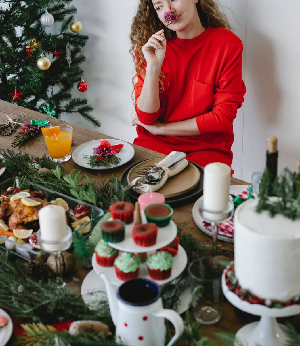 lady sitting at table with dinner near christmas tree
