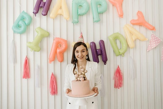 woman holding a cake and wearing a party hat