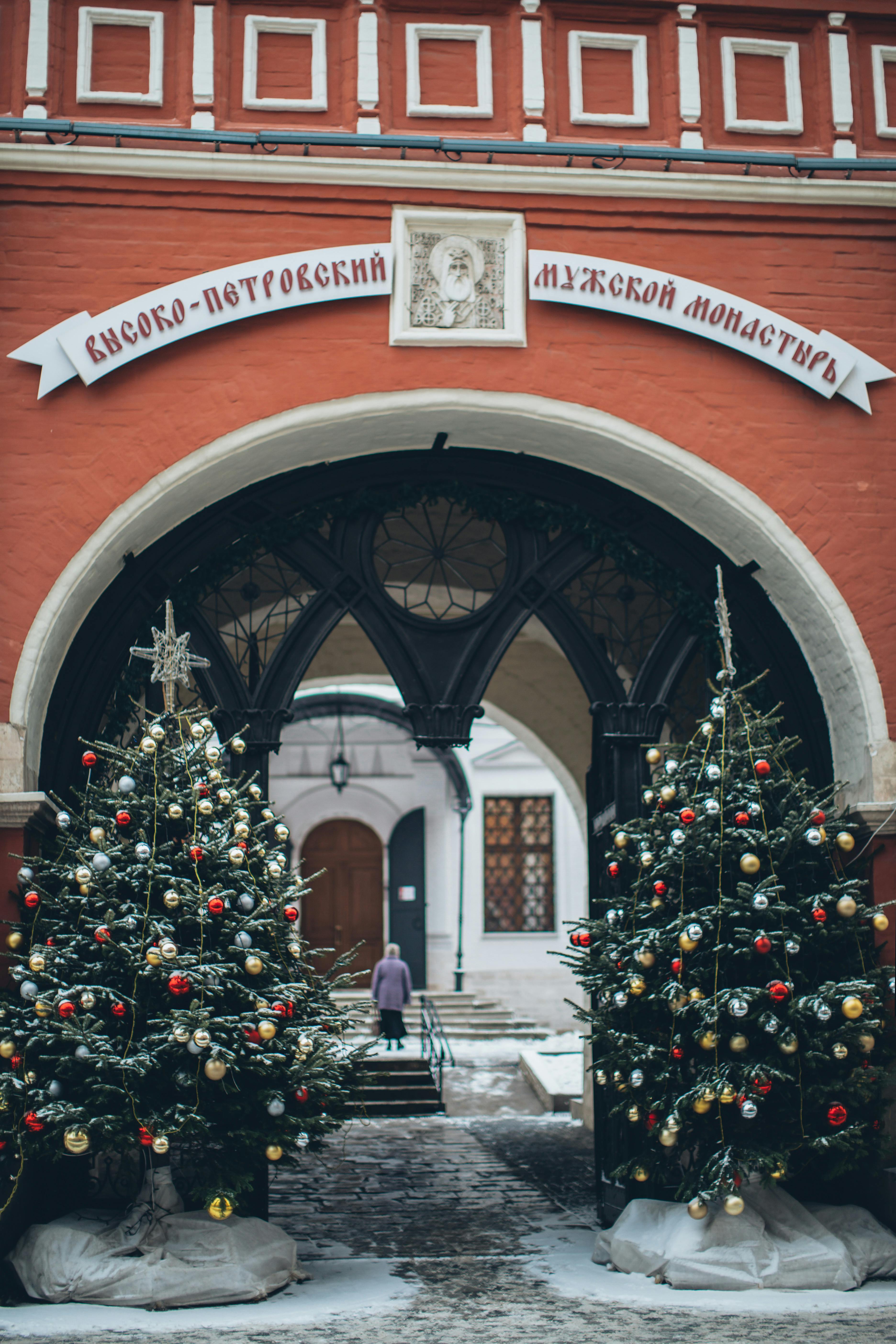 Old church facade with Christmas trees near arch entrance