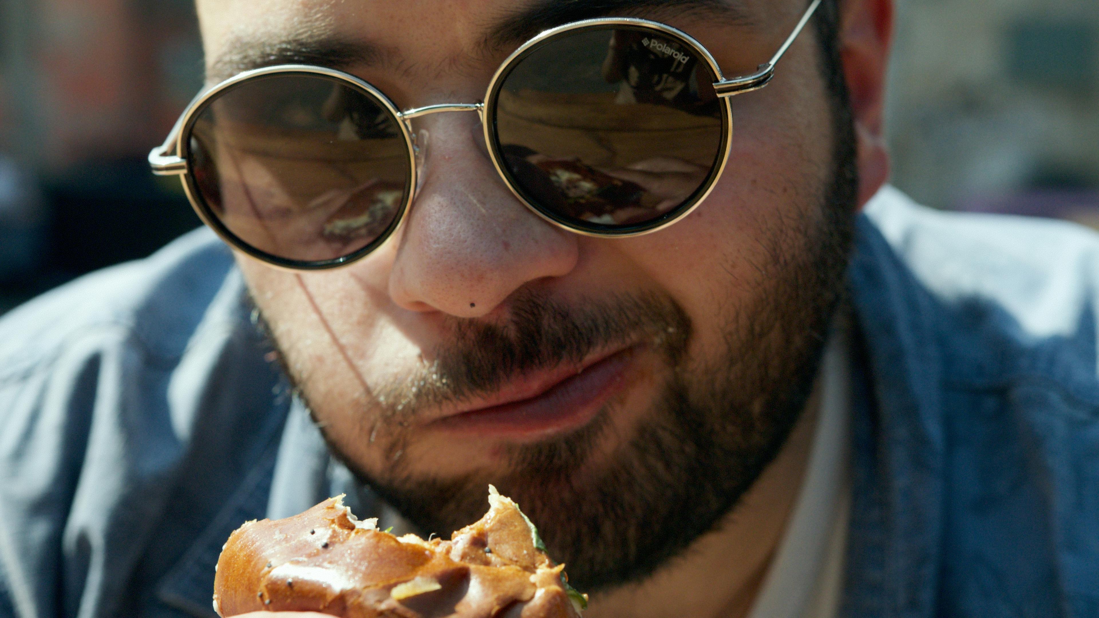 Man in Black Framed Eyeglasses Eating Pizza