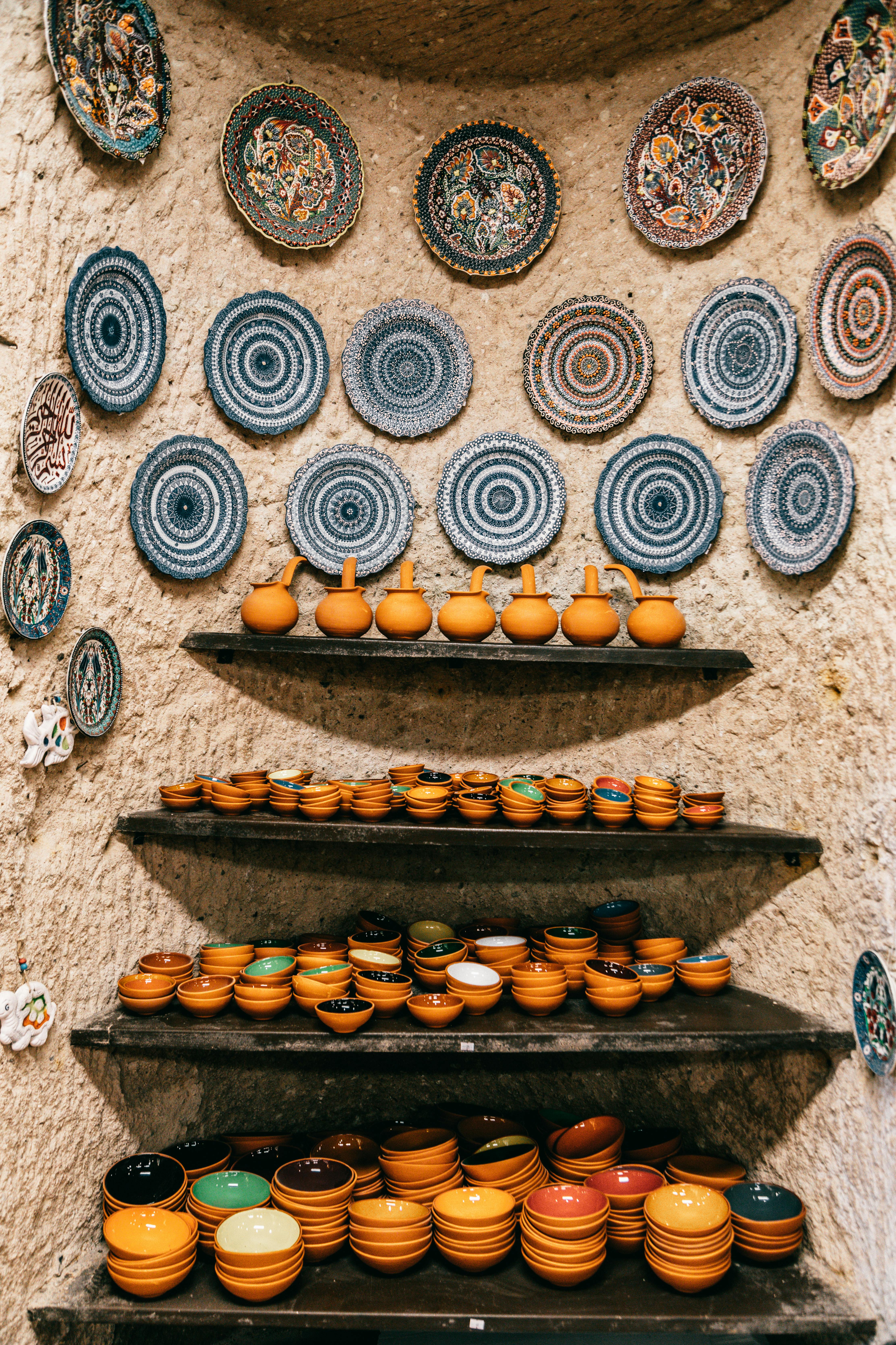 Shelves with different ceramic bowls near stone wall
